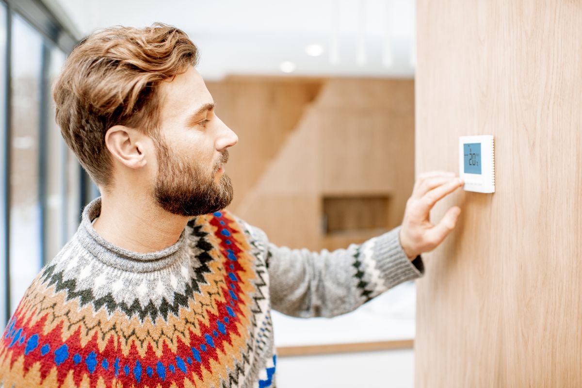 inconsistent heat man touching thermostat