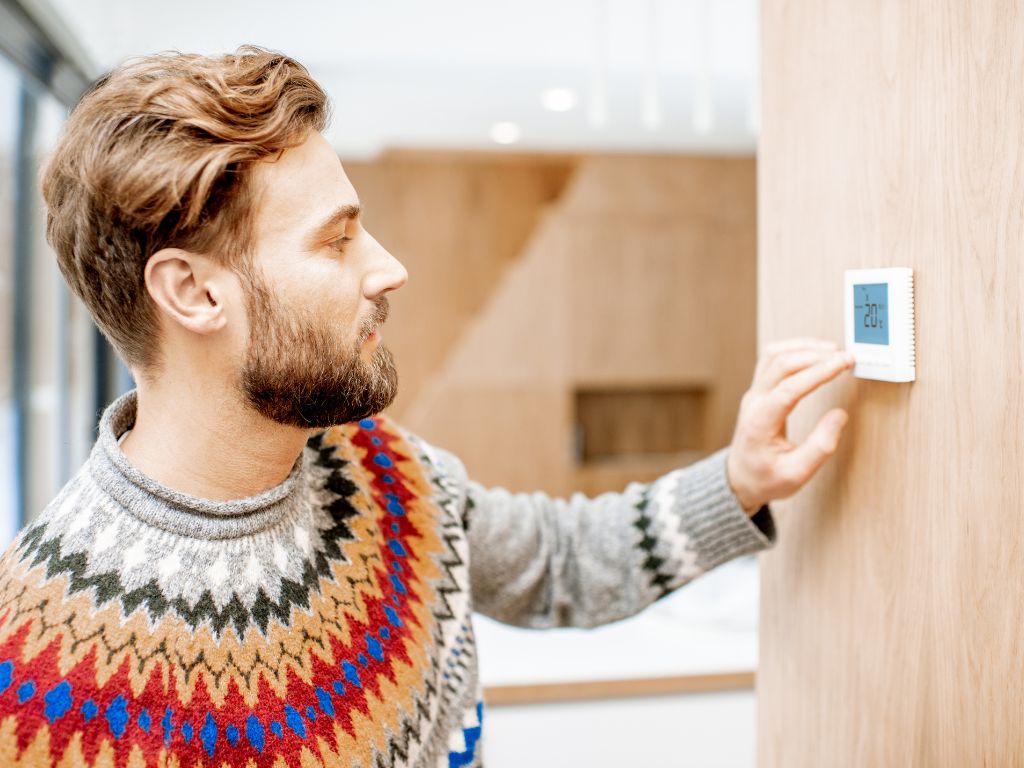 The Impact of Rising Energy Costs in Pensacola: Why Now Is the Time to Upgrade Your HVAC System 7 male adjusting thermostat
